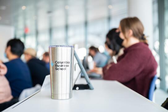 CBS branded travel mug in classroom with students
