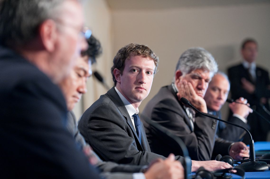 Mark Zuckerberg sits at a conference table with a group of other people