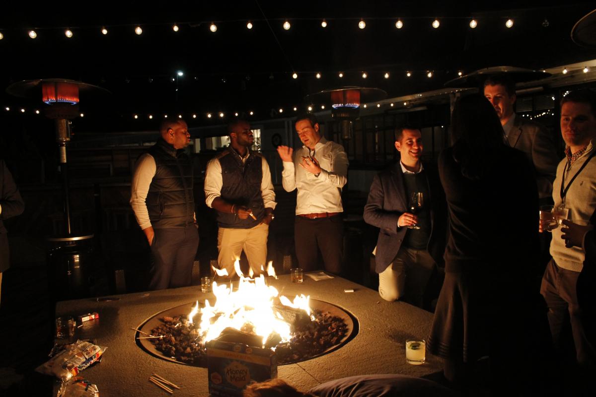 Deal Camp attendees around a fire pit, drinking wine