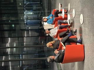 Panelists sit in red chairs, having a discussion