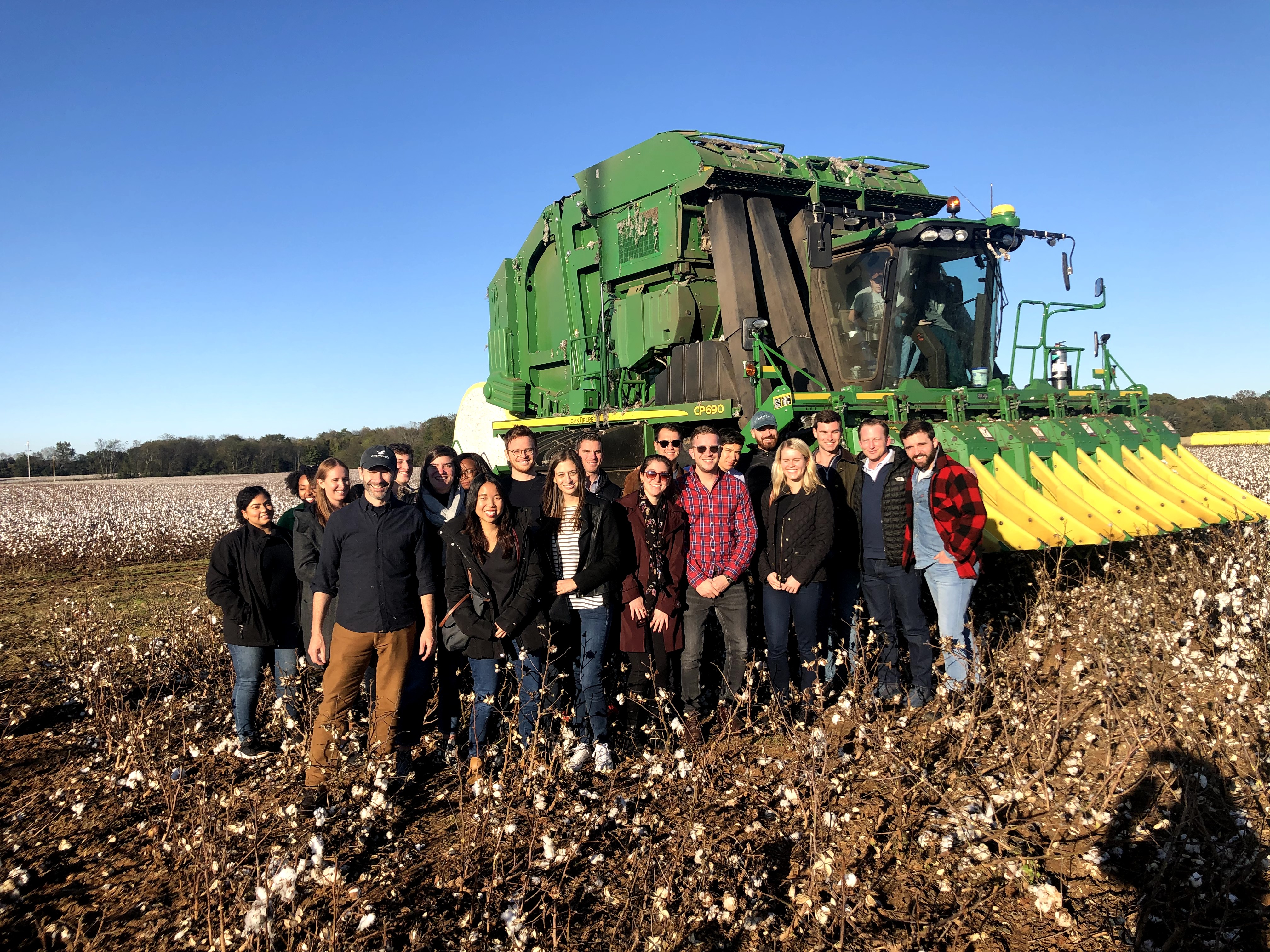 Group of students standing on farmland near a green tractor