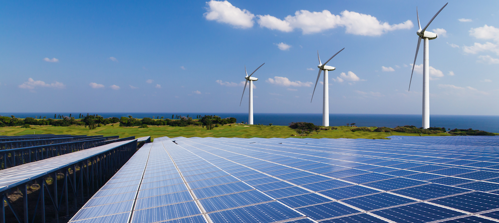 Wind turbines and solar panels against a blue clouded sky