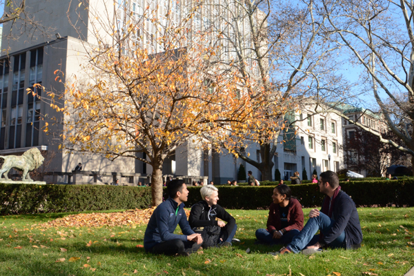 Students sitting in a circle on the grass, on crunchy fall leaves