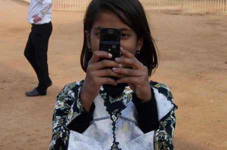 Young girl holding a cell phone to take a picture