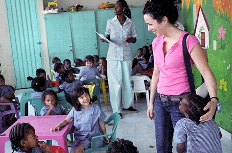 Person in a pink tshirt in a classroom setting with young children