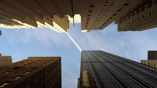 Standing in the middle of the street looking up at very very tall office buildings and a blue sky