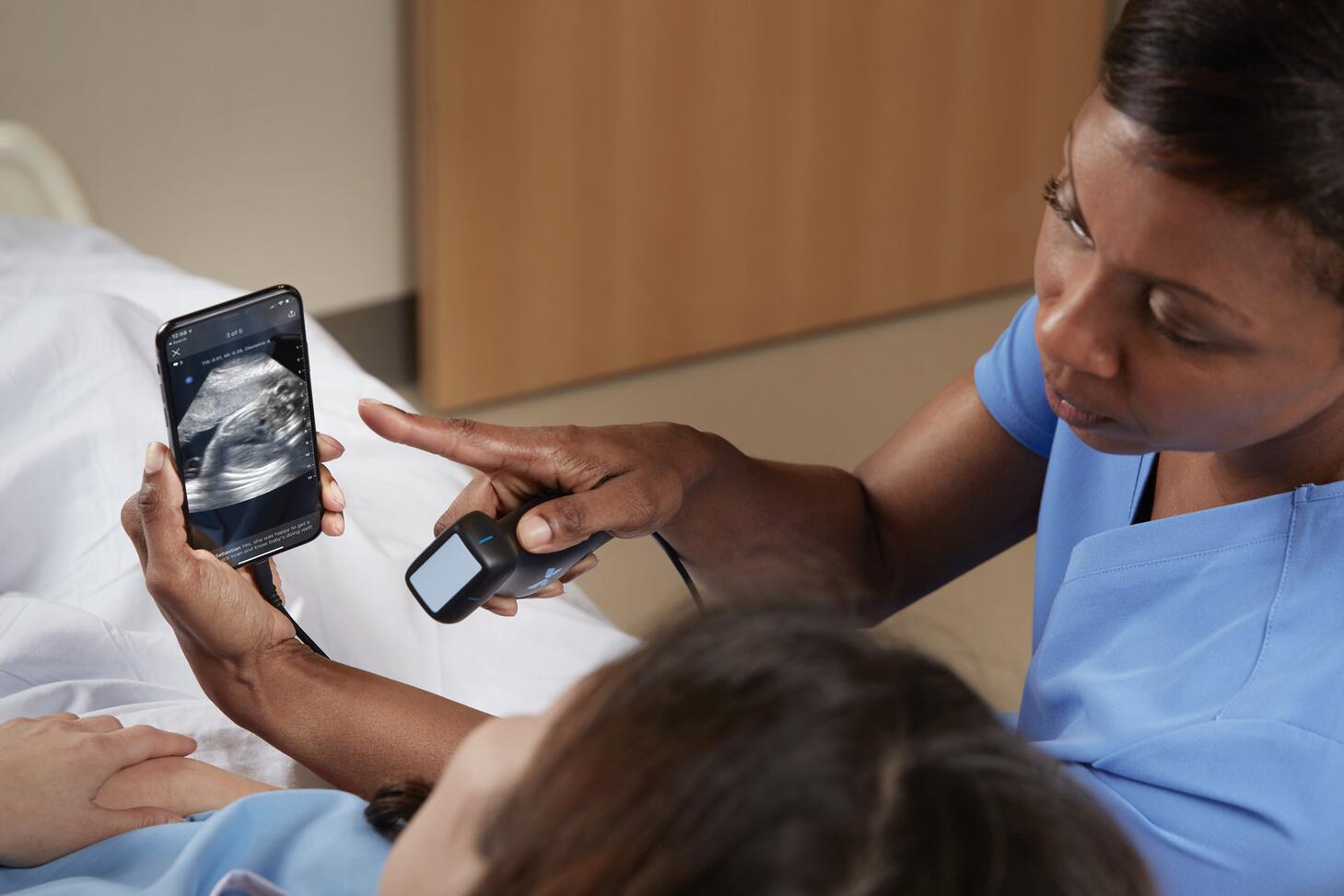 A healthcare working showing a woman a sonogram image on a cellphone.