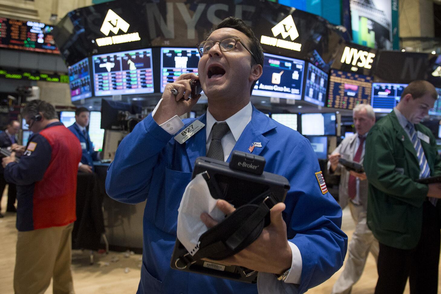 A man on a stock trading floor, talking on a phone.