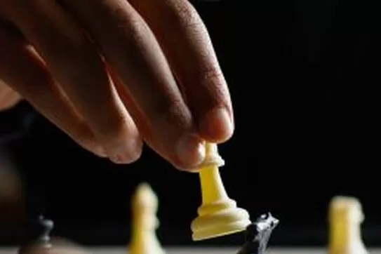 a single hand moving a chess piece