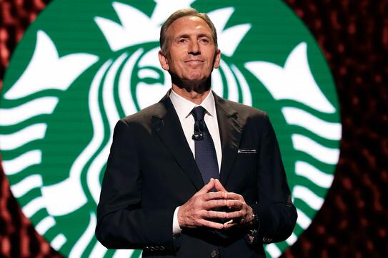 Howard Schultz in front of Starbucks logo