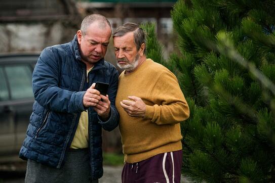 Two men discussing bad news, looking at the screen of a smartphone