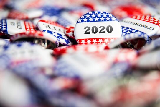 A pile of pins some that say, vote and some take 2020.