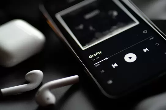 Phone with ear buds and music on the screen