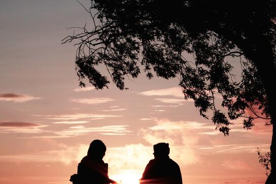 a photo of 2 people sitting in chairs in front of a sunset