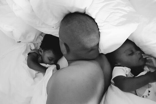 Image of a father in bed with his two children