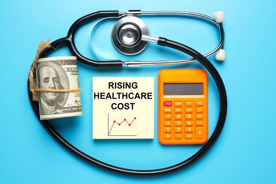 Stethoscope, fake money and calculator with notepad written Rising Healthcare Cost. Healthcare cost become more expensive after covid-19.