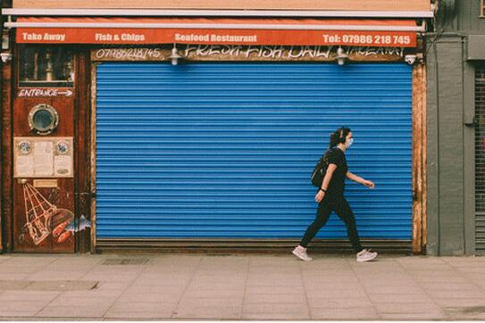 person walking past a shuttered business
