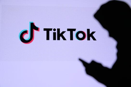A person using a mobile device next to a TikTok logo