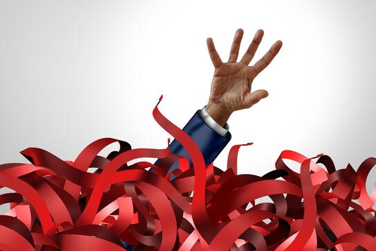 A hand reaching out of a sea of red tape
