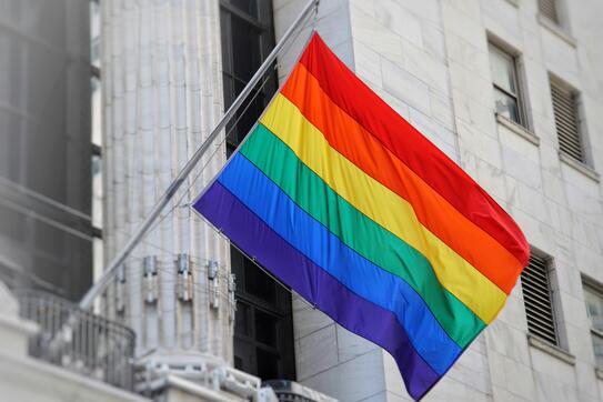 rainbow Pride flag flying in front of a neoclassical office building