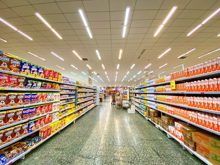 A brightly lit supermarket aisle; photo by Nathália Rosa on Unsplash