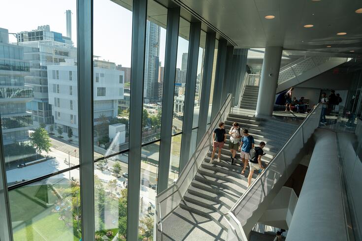 A sweeping view of the wide staircase inside Kravis, with a handful of students talking to each other on the stairs