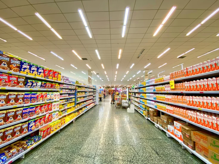 A brightly lit supermarket aisle; photo by Nathália Rosa on Unsplash