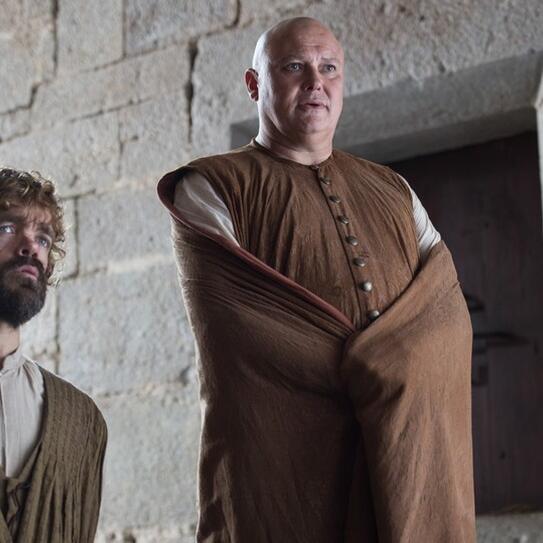 Image of Game of Thrones characters Varys and Tyrion Lannister standing in front of a stone wall