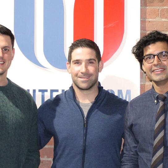 Taylor Justice, Dan Brillman, and Fahad Ahmed standing in front of the Unite US banner